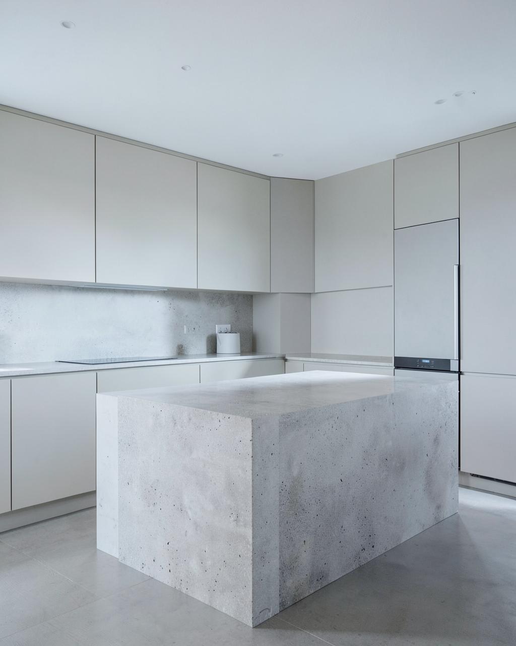 Minimalist kitchen with handle-less pale cabinets and a single stone island